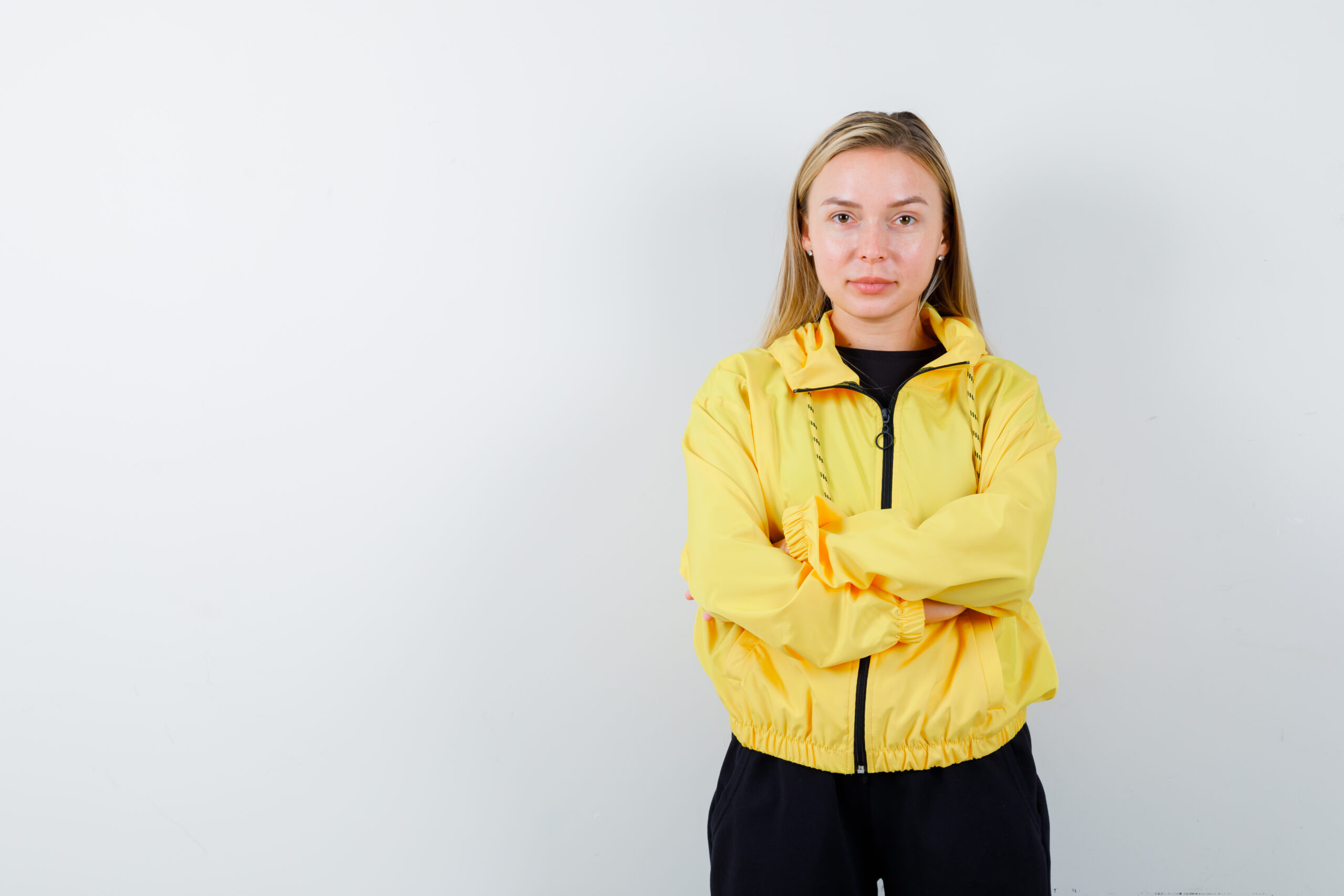 blonde lady in tracksuit holding arms folded and looking confident , front view.