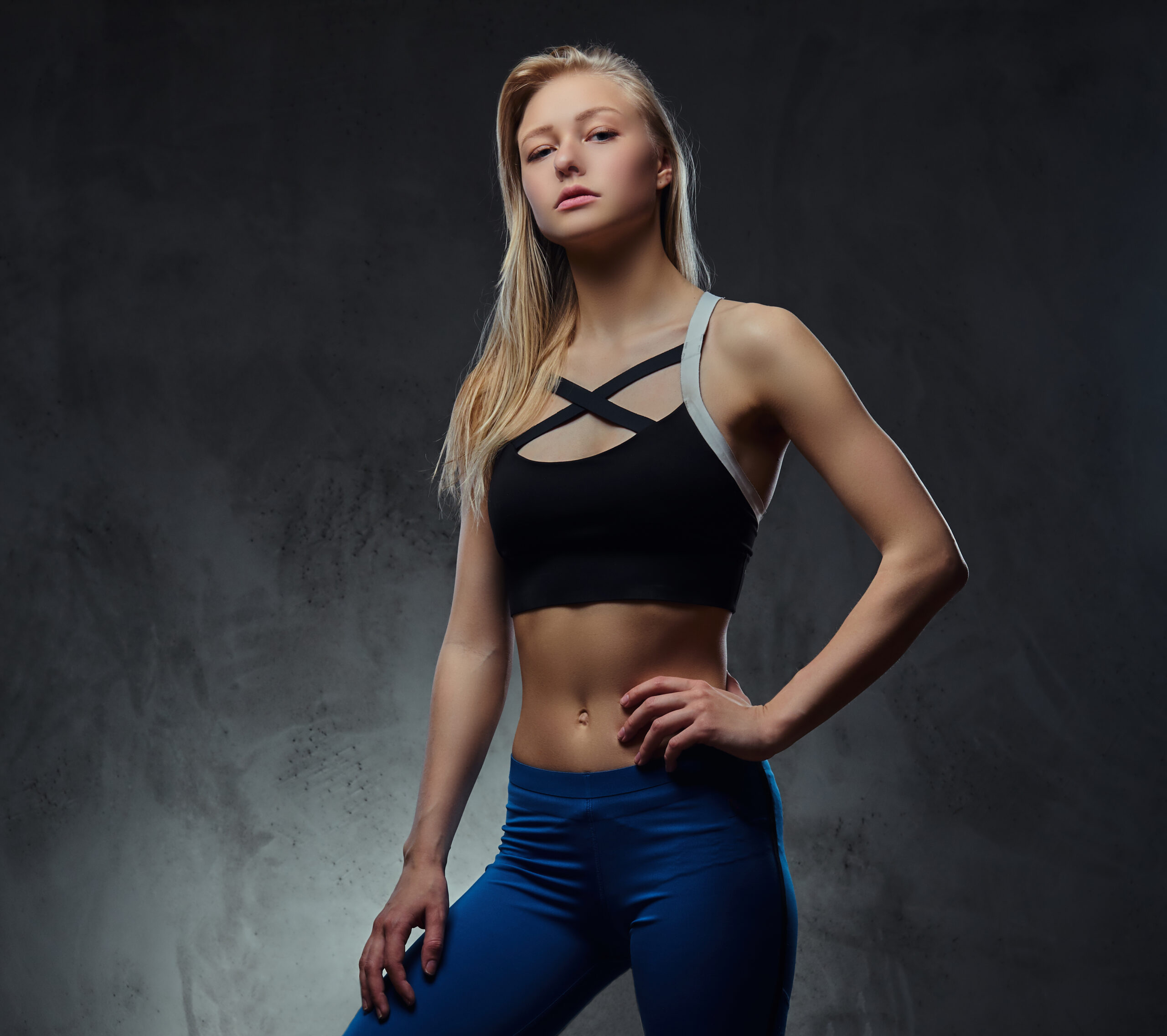 sexy slim blonde girl in a sportswear posing in a studio.